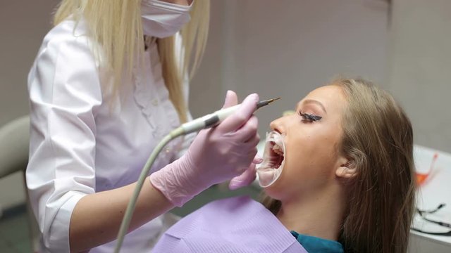 Girl is afraid of dental treatment. Portrait of scared girl in dentist cabinet. Girl with a expander mouth at the dental clinic.