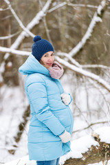 Young beautiful pregnant woman, walking in winter park