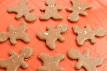 Homemade Christmas cookies background. Sweet dough for gingerbread men prepared on silicon baking mat. 