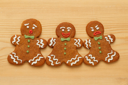 Christmas gingerbread men cookies on wooden background. Three emotional characters included - surprised, happy and angry.