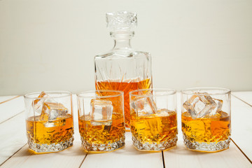 Glasses of whiskey with ice on a white wooden table