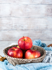 Fresh apples in basket on wooden background. Vertical