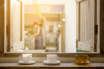 Coffee cups on opened grunge wooden window pane with outdoor view