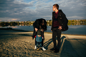 young family and son walk along the lake shore