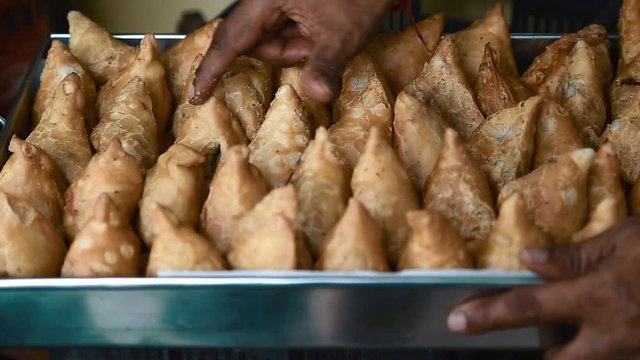 Hand counting samosas in a tray