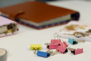 Fototapeta premium Notebooks in hand and colorful binders on the table. Glass full of pens and pencils, colored decorative tape.