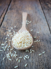Closeup Jasmine rice in wooden spoon on wooden table background.