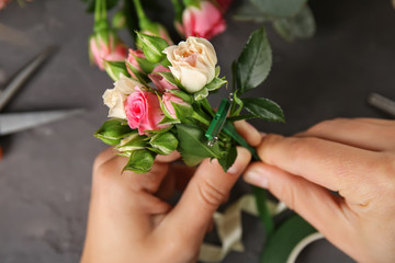 Female hands making beautiful bouquet of flowers on dark background