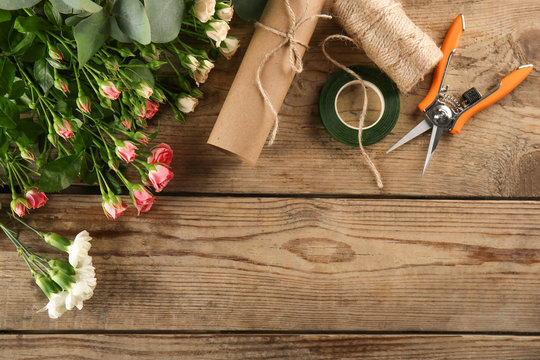 Beautiful flowers and florist equipment on wooden background