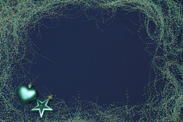 Festive frame in the form of tinsel. Christmas/New year toys. Dark blue background, copy space, text area, flat lay