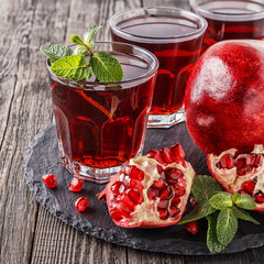 Glasses of pomegranate juice with fresh pomegranate fruits