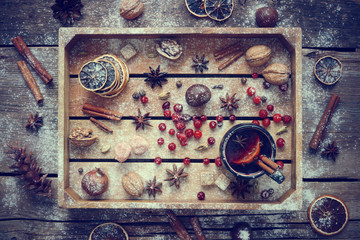 Mulled wine in mug with spices and ingredients in wooden box.