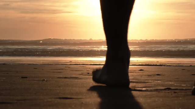 Model released person walks out on sandy beach and into the Pacific on beautiful sunny evening at the Oregon Coast.