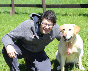 young man with blacks hair smiling with labrador retriever