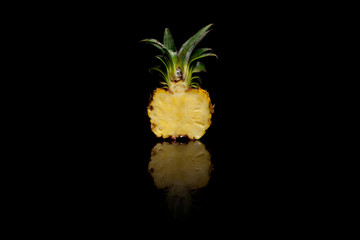 Half of mini pineapple on black background