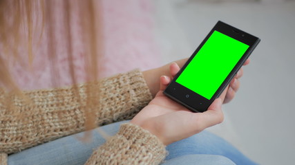 Woman looking at smartphone with green screen. Close up shot of woman's hands with mobile