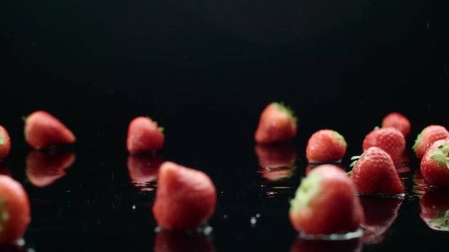 strawberry rain, juicy ripe berries fall from the water in slow motion, black background
