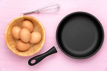 Cooking background with eggs,pan,on a pink wooden background. Top view.