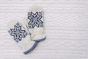 Pair of mittens on white knitted background