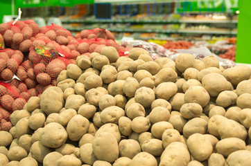 Close up of white and sweet potatoes on market stand.