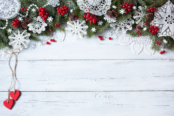 Fototapeta na wymiar Christmas wooden white background with snowflakes, heart, tree branches and red berry