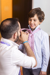Obraz na płótnie Canvas Father is helping his son to wear the tie.