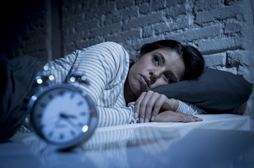 hispanic woman at home bedroom lying in bed late at night trying to sleep suffering insomnia