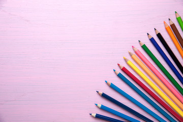 color pencils on pink wooden background