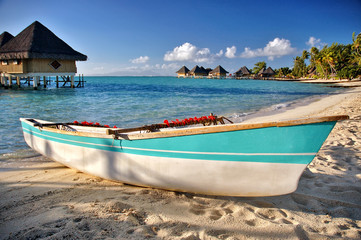 Fototapeta na wymiar Boat on Bora Bora beach with blue ocean, bungalows background