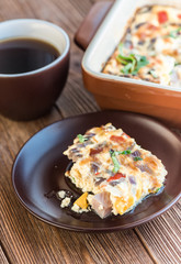 Omelet with ham and cheese  in a baking form. Cup of coffee.