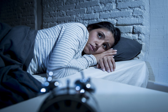 hispanic woman at home bedroom lying in bed late at night trying to sleep suffering insomnia