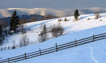 Fenced pastures covered with snow on a mountain slope in winter.