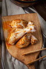 Marinated chicken drumsticks on a wooden chopping board.