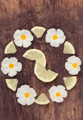 White flowers with lemon slices arranged in a flower pattern on an old wood