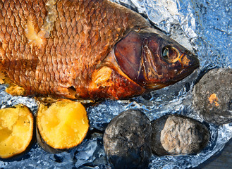 River fish baked in foil on fire and baked potato.