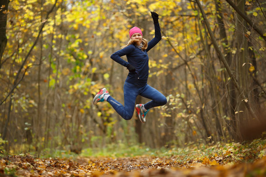 Sportswoman running among autumn leaves