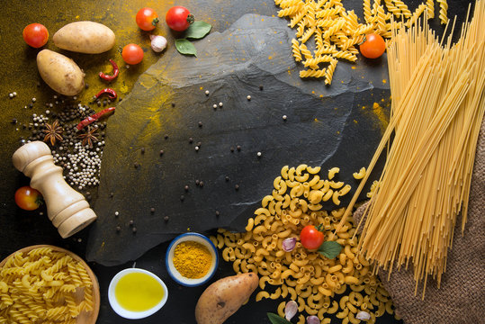 vegetables and spices for tomato sauce,pasta tagliatelle with tomatoes on dark background, top view