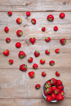 Flatlays. Top view of fresh strawberries scattered and in a plate on a wooden surface