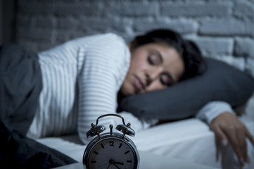 hispanic woman at home bedroom lying in bed late at night trying to sleep suffering insomnia