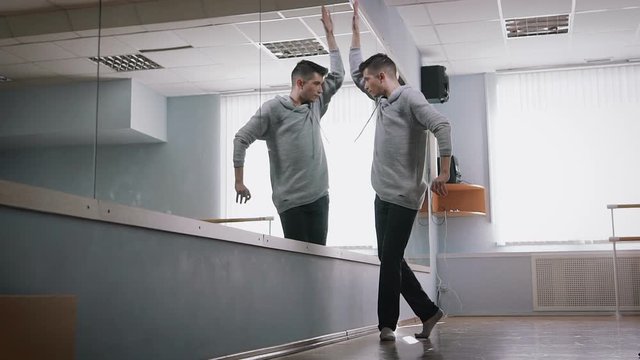 Rehearsal hall. The dancer rehearses dance a modernist style. He is dressed in the black fitting trousers and a free jacket. Nothing has to hinder his movements.