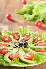 Sliced avocado with salad leaves, cherry tomatoes, olives and gr