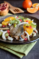 Fried trout fillets garnished with fennel, orange, raisins and pomegranate salad