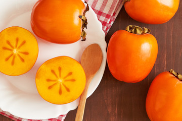 Japanese persimmon (Diospyros kaki) served on white plate. Top view