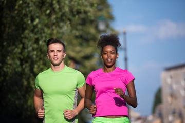 Obraz premium young smiling multiethnic couple jogging in the city
