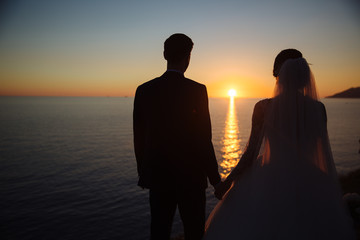groom and bride are holding hands at sunset, wedding day. Concept of love family