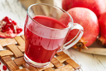Glass of pomegranate juice with fresh fruits on white rustic wooden table