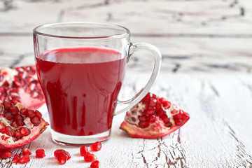 Glass of pomegranate juice with fresh fruits on white rustic wooden table. Copy space
