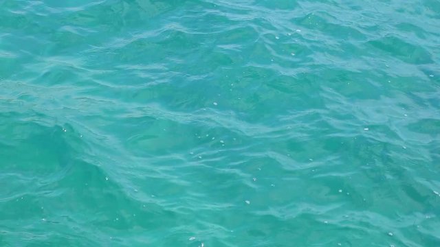 Aquamarine color nature background. Close up of sea water surface of bright blue color on sunny summer day. Real time full hd video footage.