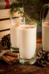 Traditional Christmas alcoholic cocktail - Irish Cream, Cola de mono (monkey tail), decorated with cinnamon. Against the background of Christmas decorations on a wooden table. Close view