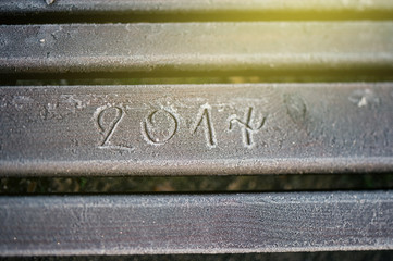 2017 numbers written on a covered with snow and frost park bench during a cold morning